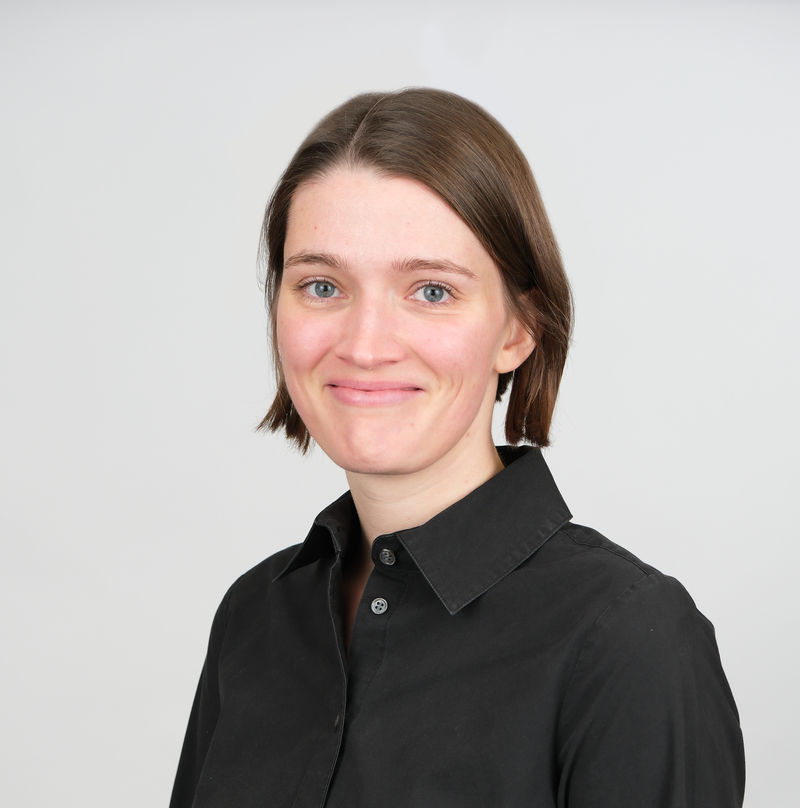 Woman with chin length brown hair and a black shirt slightly smiling at the camera